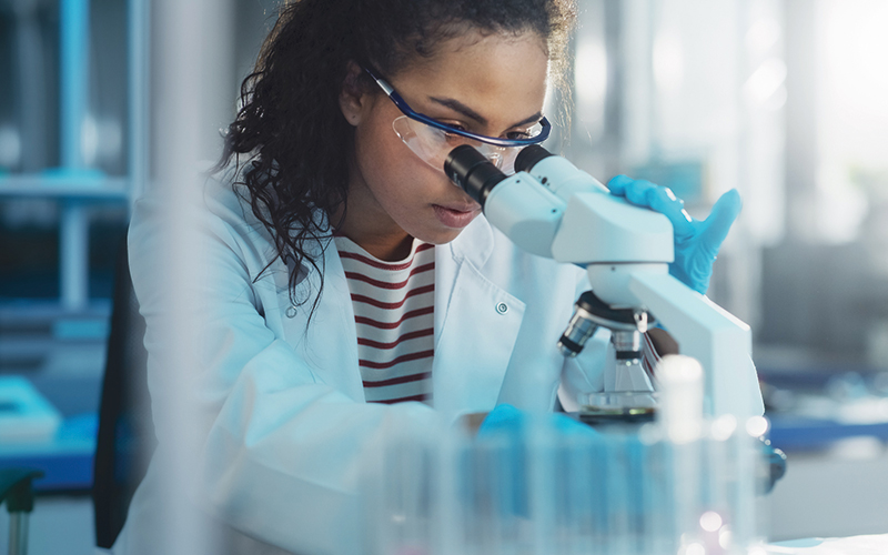 Medical Science Laboratory: Portrait of Beautiful Black Scientist Looking Under Microscope Does Analysis of Test Sample.Credit-istock-1346675662